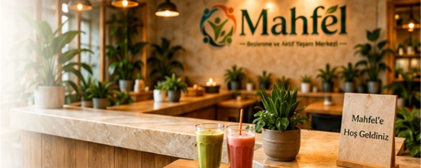 Mahfel’de ahşap tezgâh üzerinde smoothie’ler, bitkiler ve Hoş Geldiniz tabelası